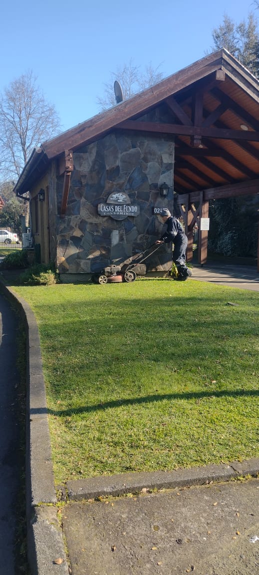 Jardinero cortando césped en acceso del Condominio Casas del Fundo en Temuco
